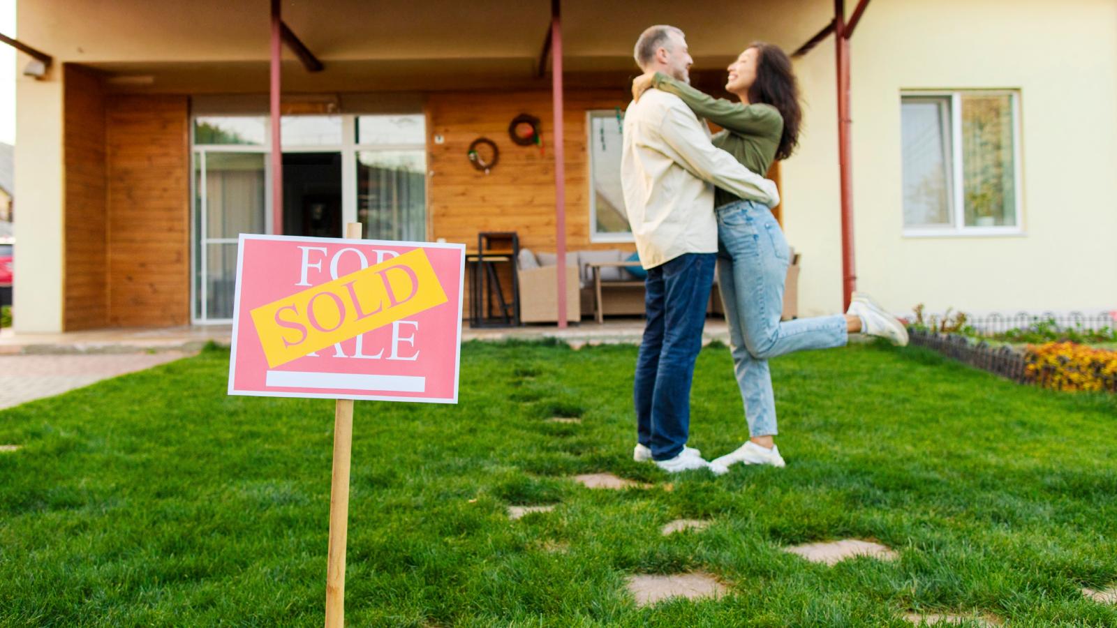 A Homeowner Fired His Shady Realtor and Sold the House Himself—Saving Thousands in the Process couple in front of a sold house
