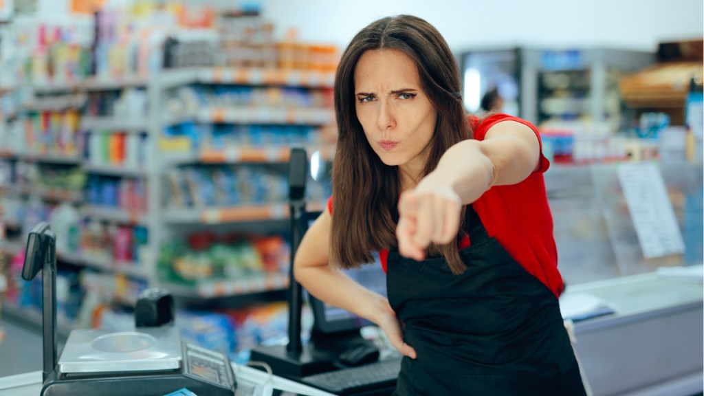 A cashier points at someone in anger