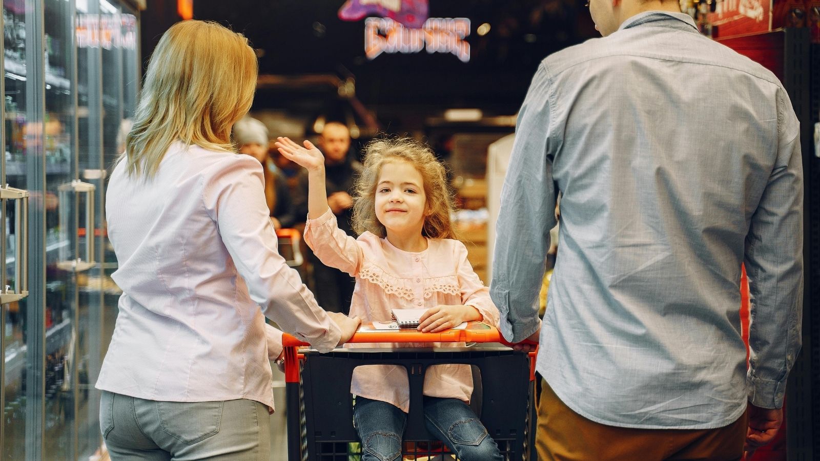 child in a shopping cart with her parents