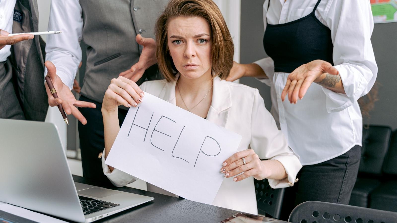 stressed employee holding up sign that says help