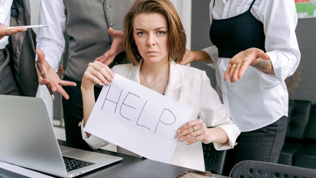stressed employee holding up sign that says help