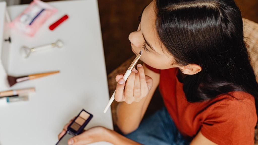 teenager in red shirt putting on makeup