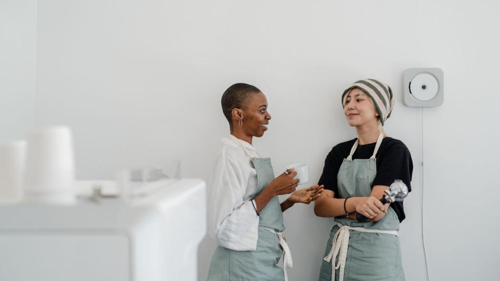 two baristas talking in green aprons