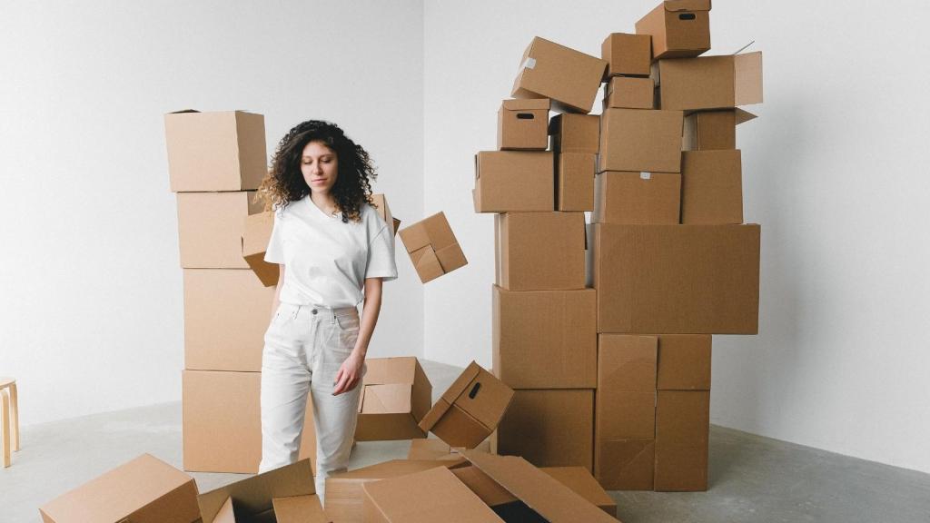 woman standing next to pile of moving boxes