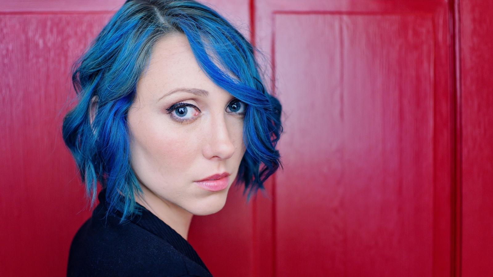 Manager Saw Her Blue Hair Before Hiring Her—So She Was Shocked When He Complained During Her First Week woman with blue hair against red door