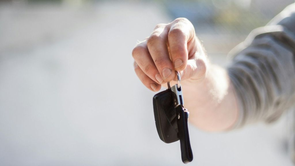 man holding out car keys