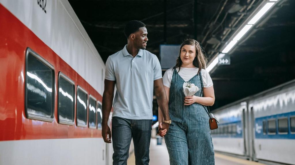 young couple holding hands at train station