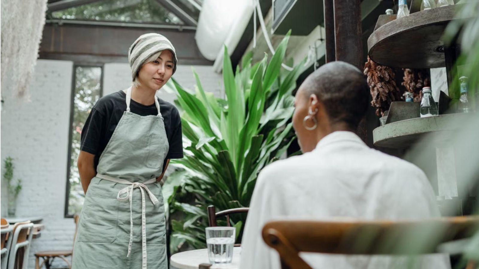 New Server Offered to Take a Coworker’s Busy Shift—But Her Manager Said She Wasn’t Ready to Work Alone Employee with apron talking to another woman sitting on a chair
