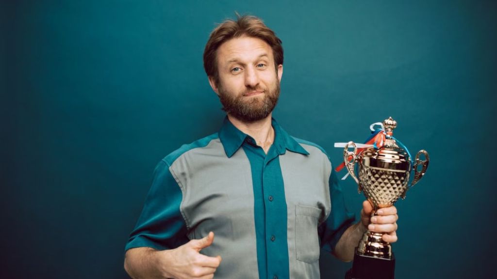 Man holding a trophy on one hand and doing a thumbs up on the other