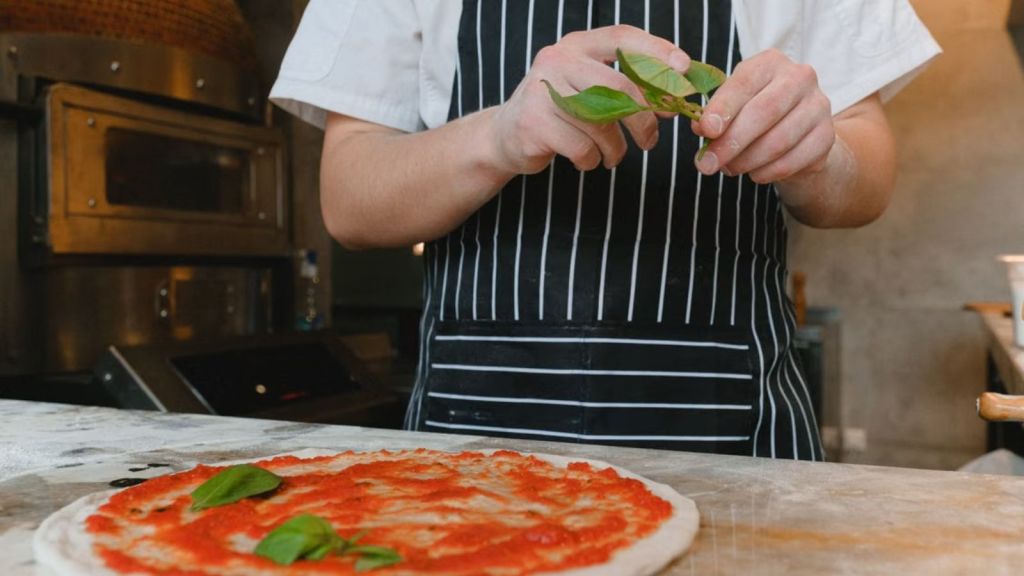 Man making pizza and putting leaves on the dough