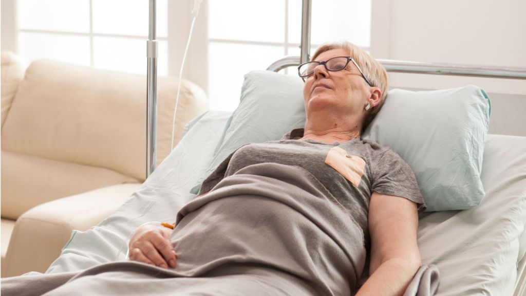 Middle aged woman lying in hospital bed with dextrose attached to her