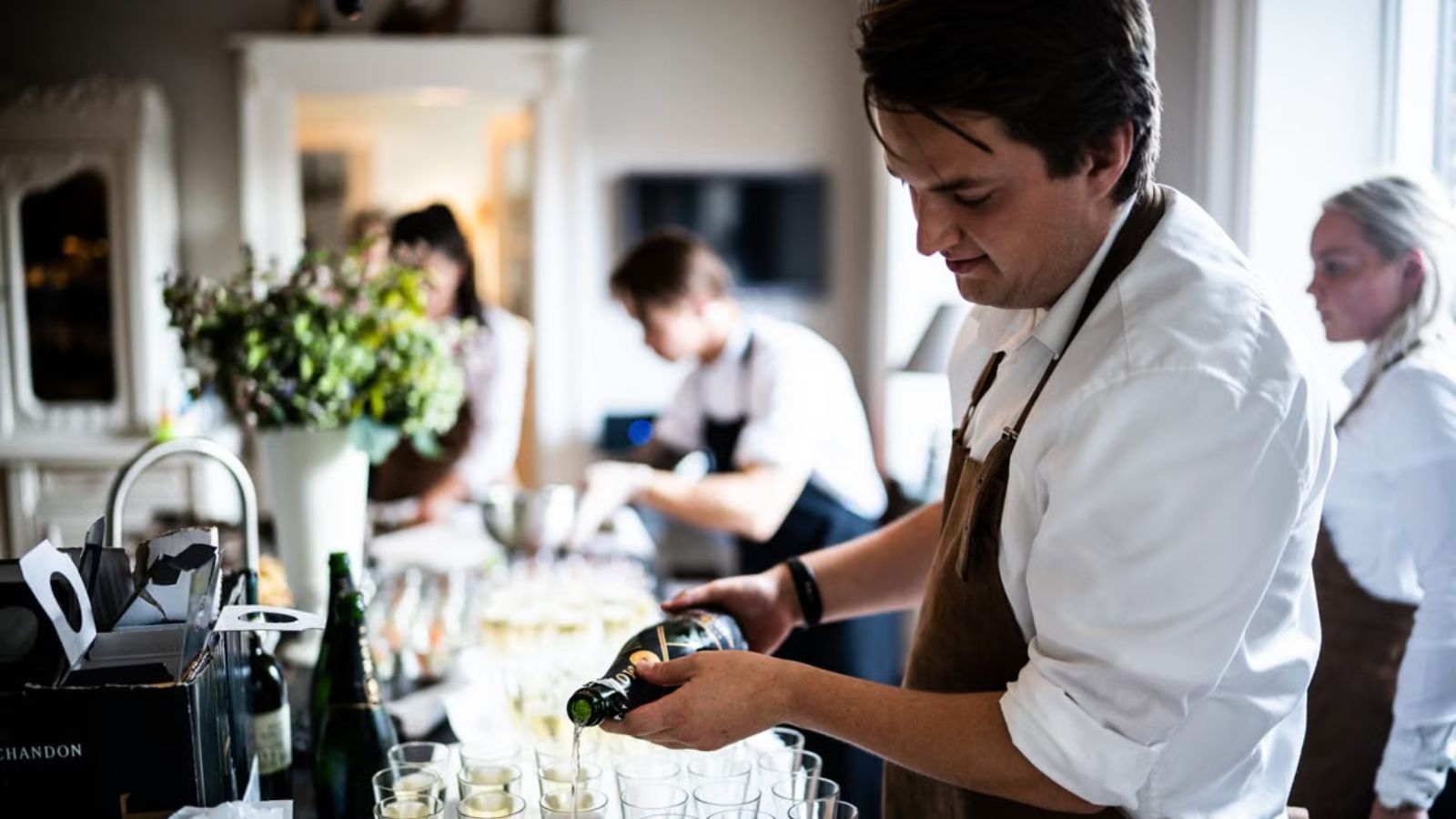 He Spent Three Years Waiting for a Regular Hotel Position—But Union Fees Have Him Rethinking Everything Several servers working at a banquet preparing foods and drinks