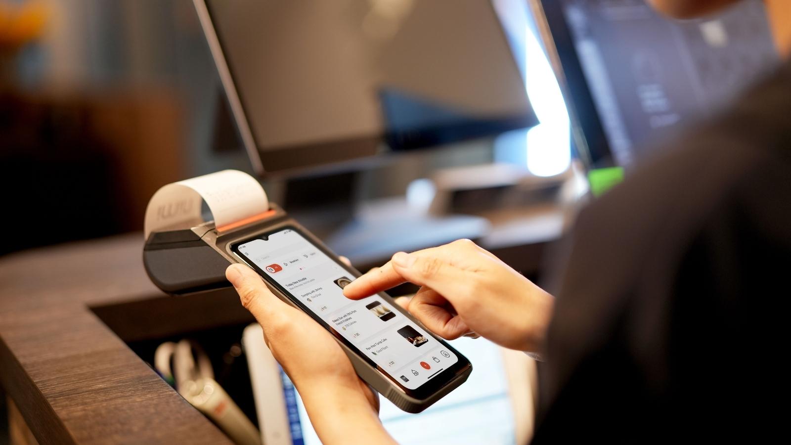 Woman holding a phone with receipt coming out the top