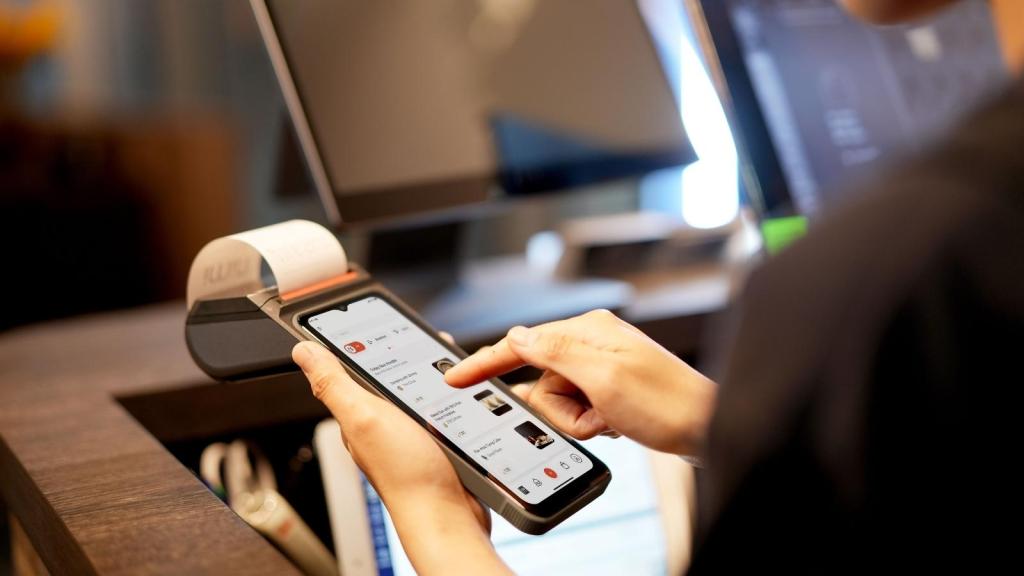 Woman holding a phone with receipt coming out the top