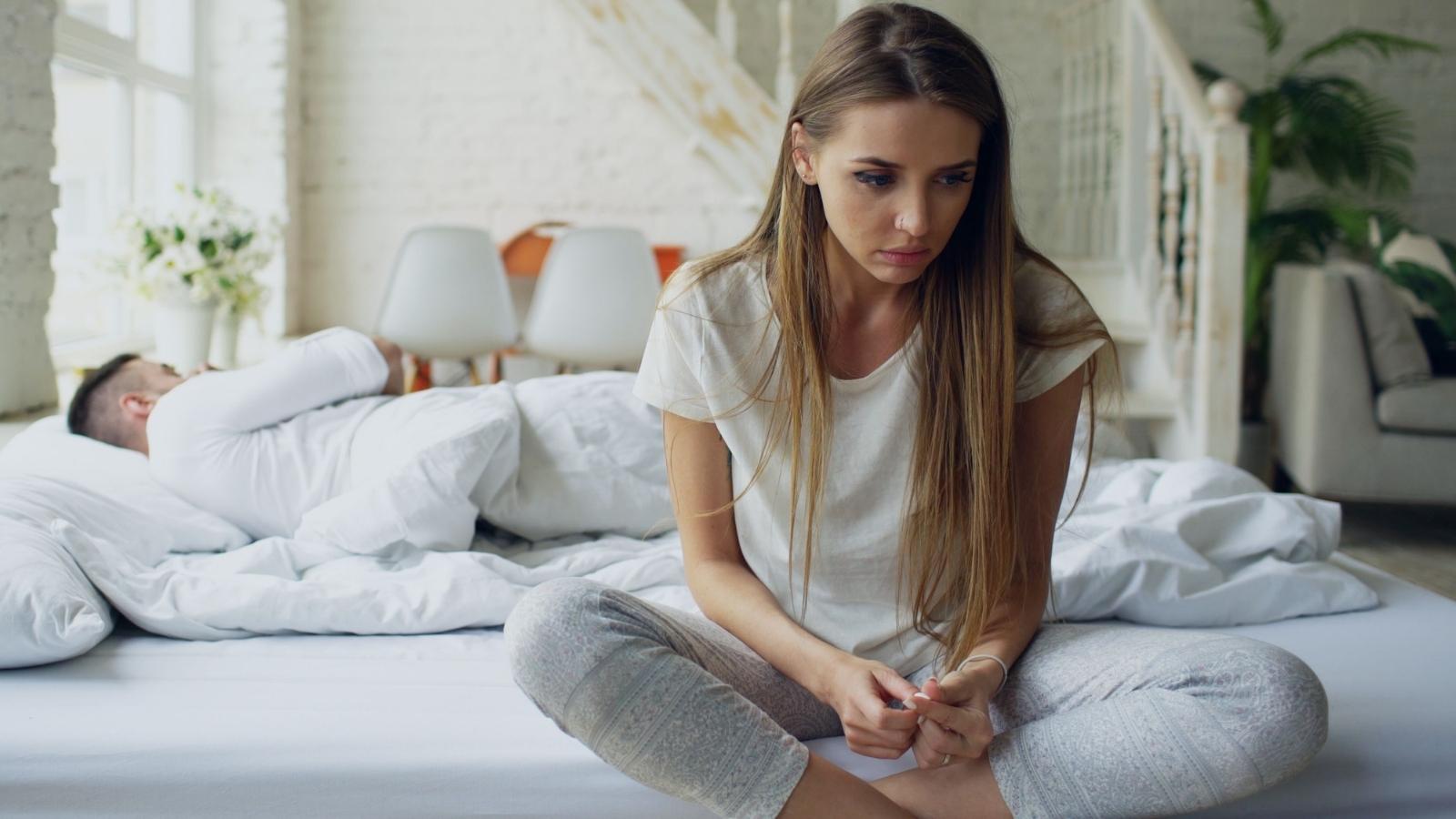 Woman sitting her bed thinking about rude dad