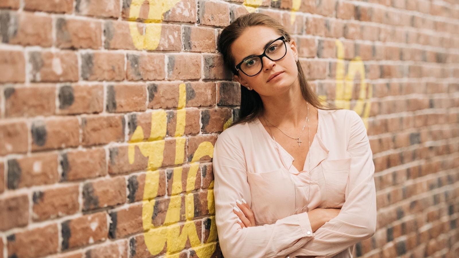Woman leaning her head up against a brick wall