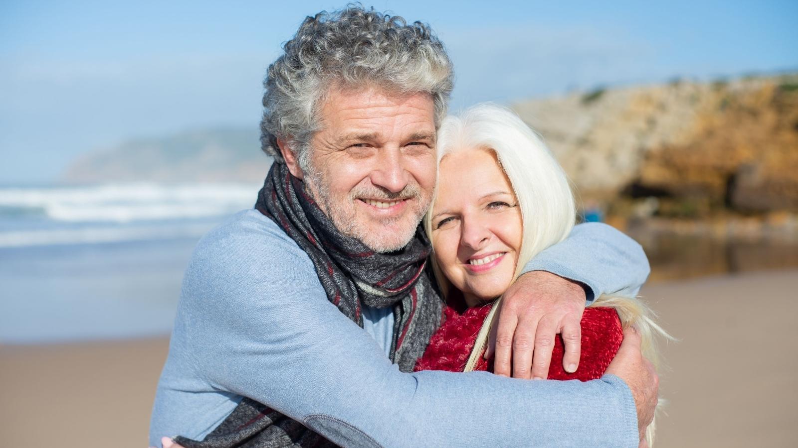 Her Siblings Paid for Their Own Weddings—Now Wealthy Parents Refuse to Help Lower Earning Daughter Older husband and wife posing near the ocean.