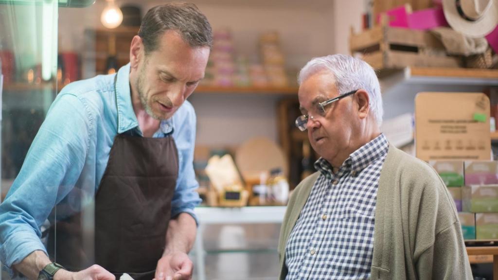 Man helping an older customer with a return