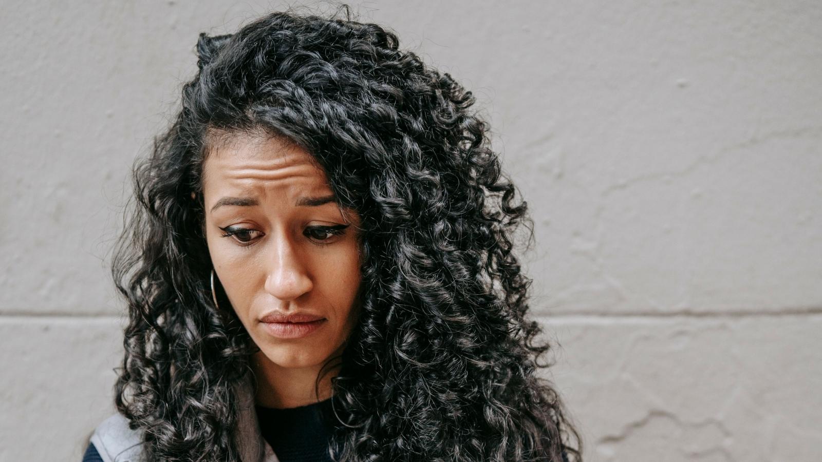 Her Neighbors Lied to the Landlord About Her 14 Year Old Brother—Nearly Getting Her Evicted Woman looking at the ground worried