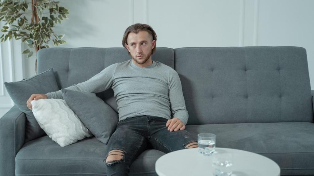 Man sitting on his couch, fed up with loud neighbors