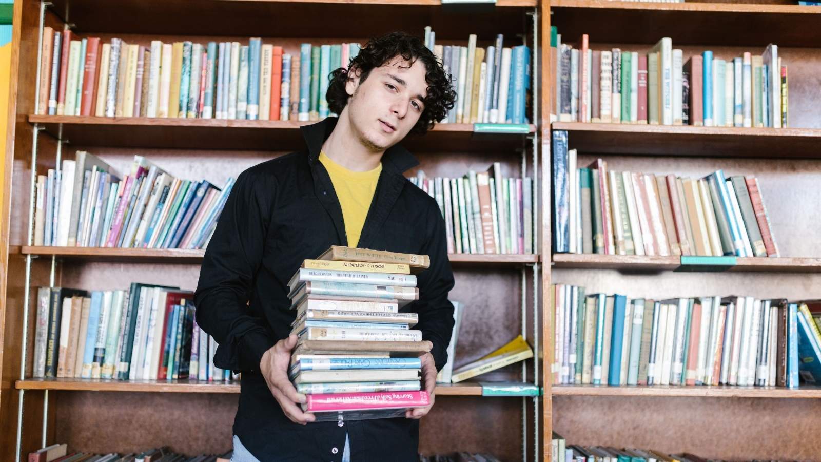 She Couldn’t Find 4XL or 5XL Shirts at the Campus Store—So She Demands a Manager and Claims Discrimination Man standing against a wall of books in a book store