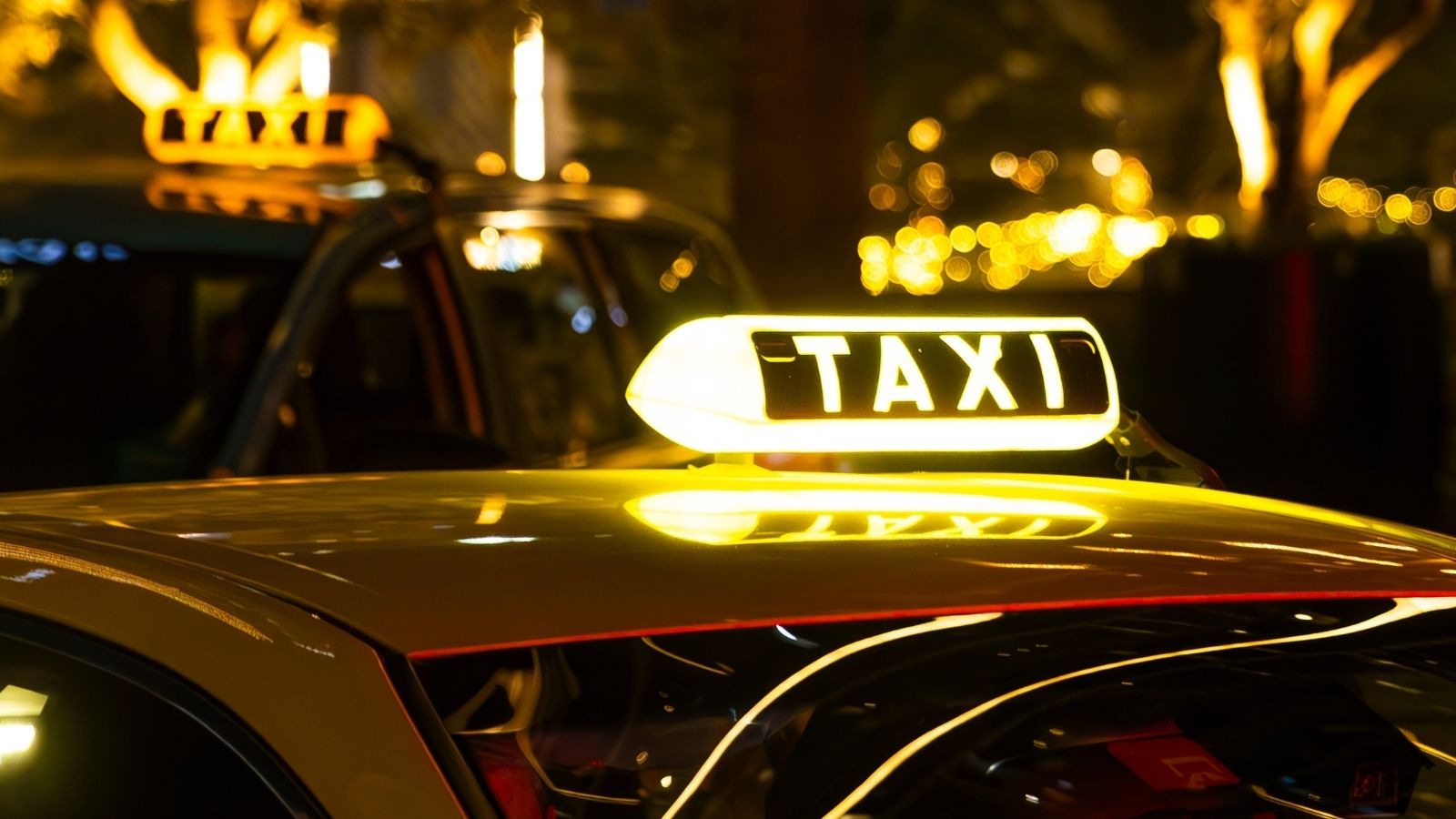yellow taxi cab with a lit-up TAXI sign on the roof