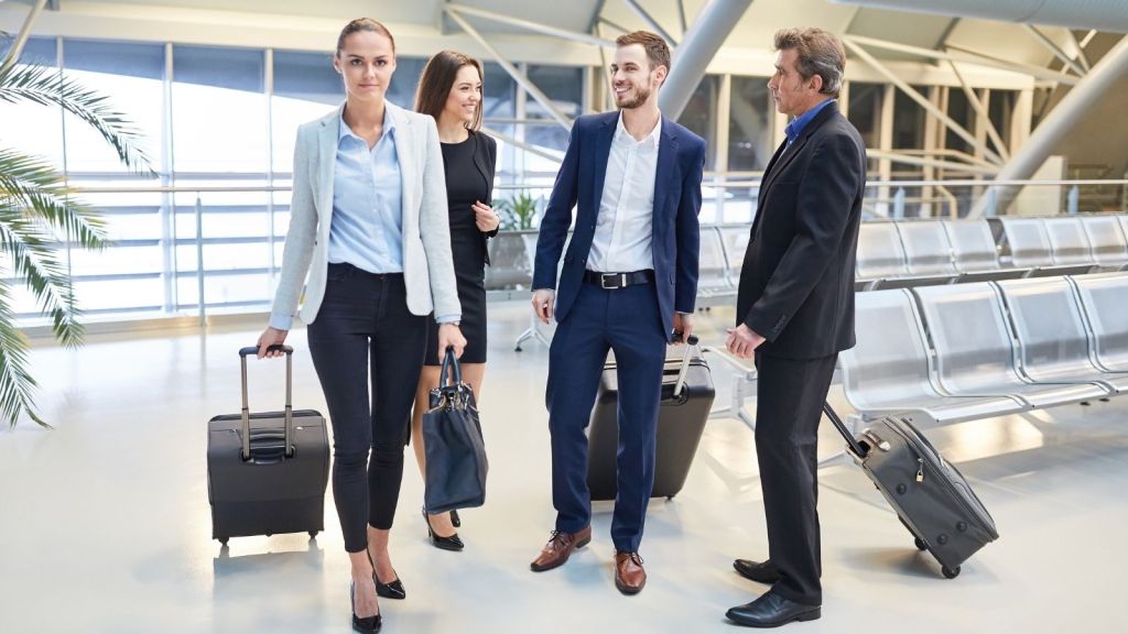 four business travelers with suitcases in an airport