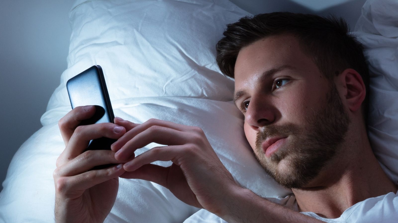 Expects Me to Answer at 2 AM: Programmer Outraged as Boss Demands Weekend Work But Denies On Call Pay man looking at his phone in bed at night