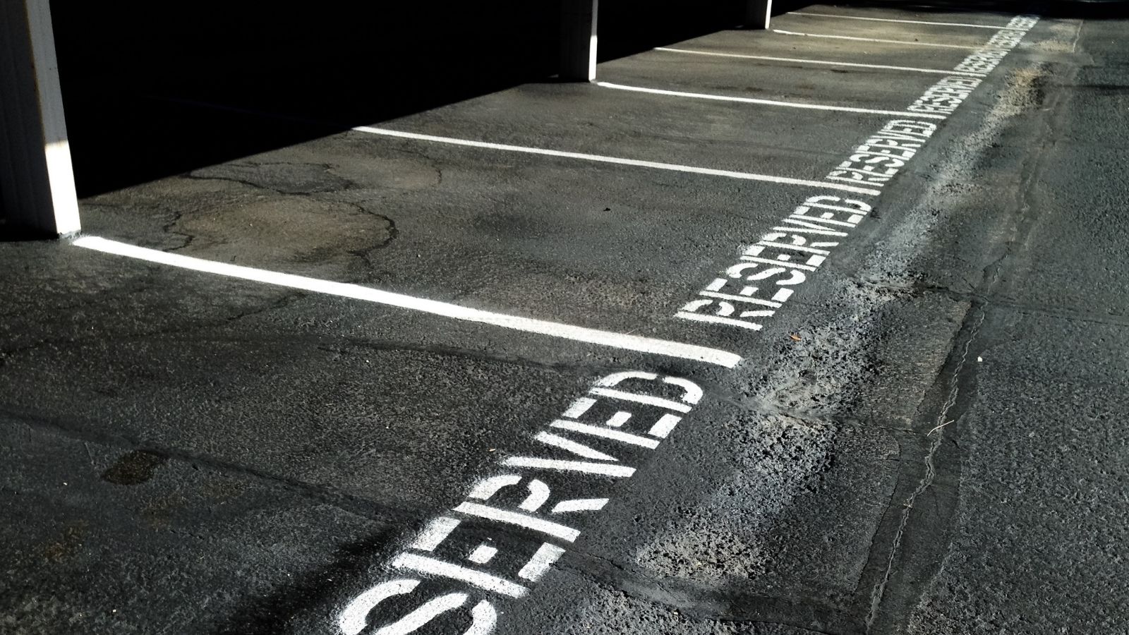 New Neighbor Took Her Assigned Parking Spot—Now Her Boyfriend Wants To Call A Tow Truck the word "reserved" written on parking spots