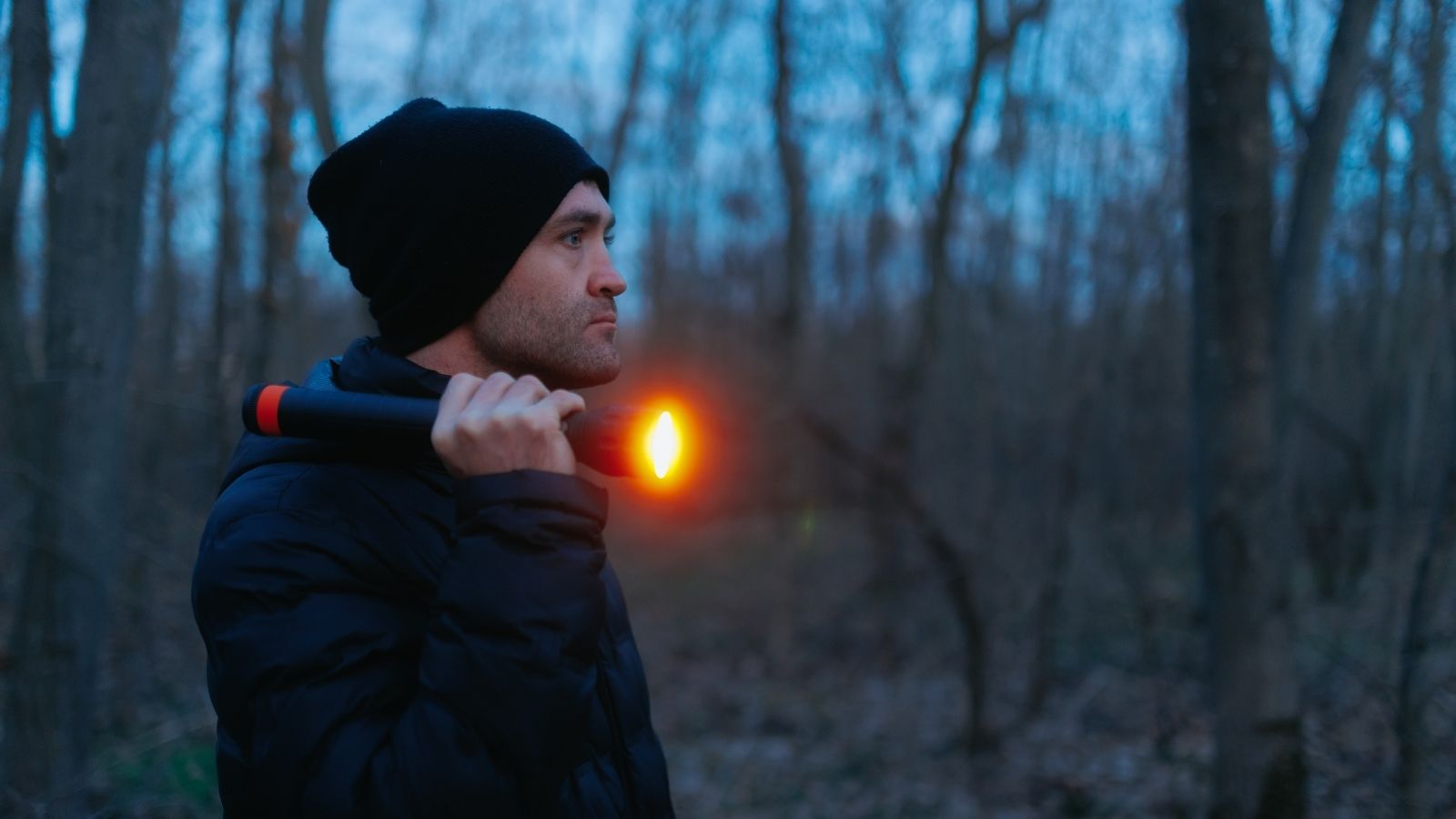 They’re Watching from the Tree Line: Landowner Finds Budget Fix to Spot Coyotes at Night man using a flashlight at night