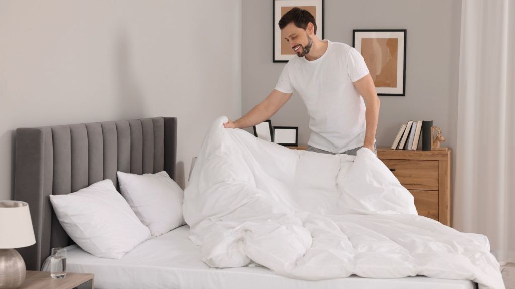 man changing the sheets on the bed