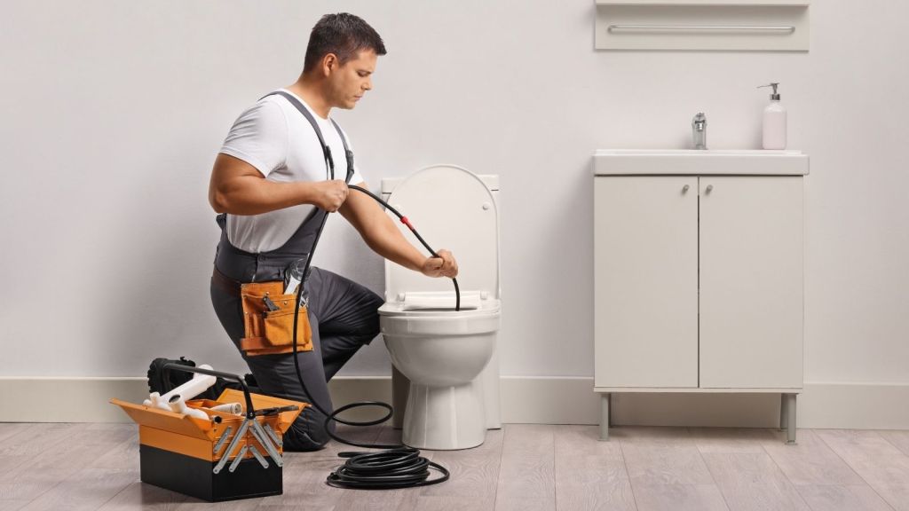 plumber using a snake to unclog a drain