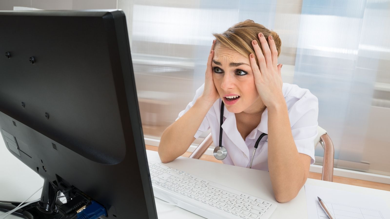 A Doctor Panicked Over a Broken Hospital Workstation—Until Tech Support Solved It by Pressing One Button young female doctor looking at computer monitor upset