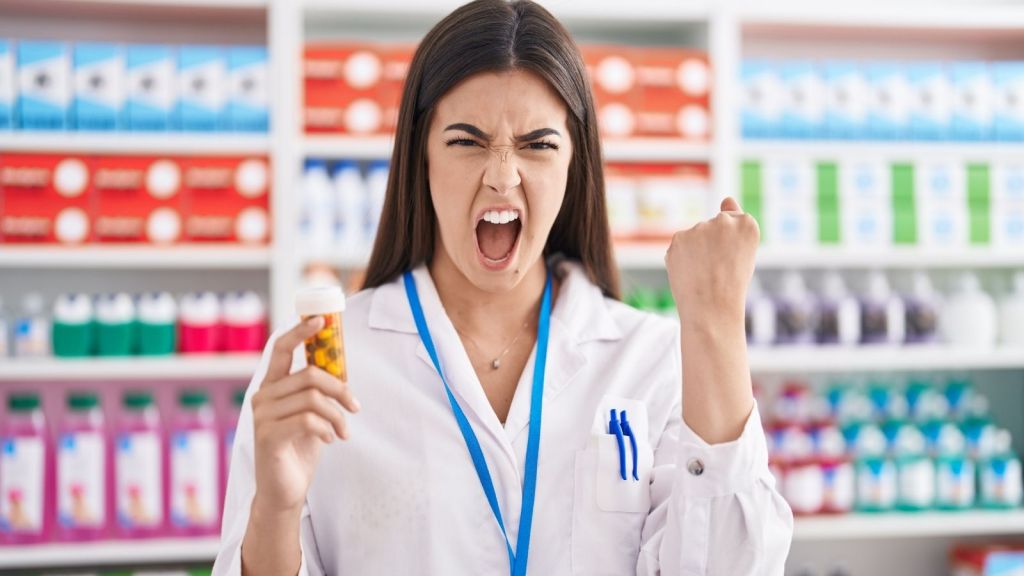 angry pharmacy employee holding bottle of pills