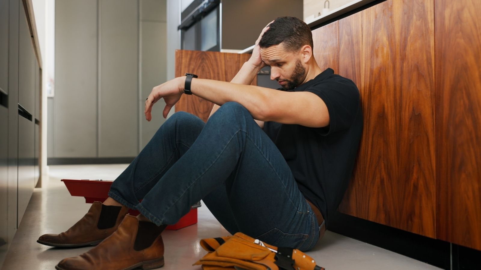 upset man sitting on the floor in the kitchen