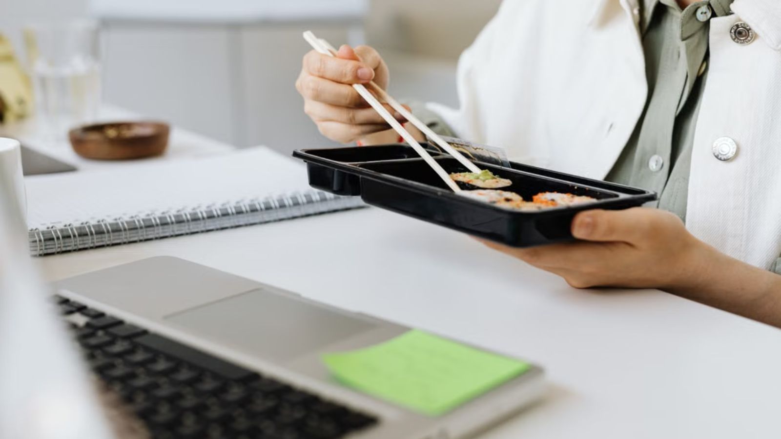 She Saw Employees Skipping Meals For Shakes—And Started Questioning The Workplace Culture Employee eating food with chopsticks in front of the laptop