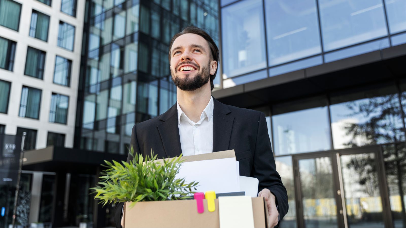 After Years Of Anxiety At Work, He Finally Quit—And Felt An Unexpected Relief Man smiling while holding a box of office things outdoors