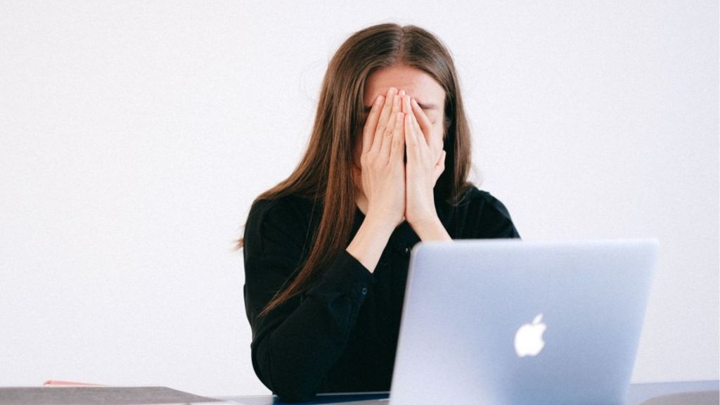 Woman feeling frustrated at work and covering her face