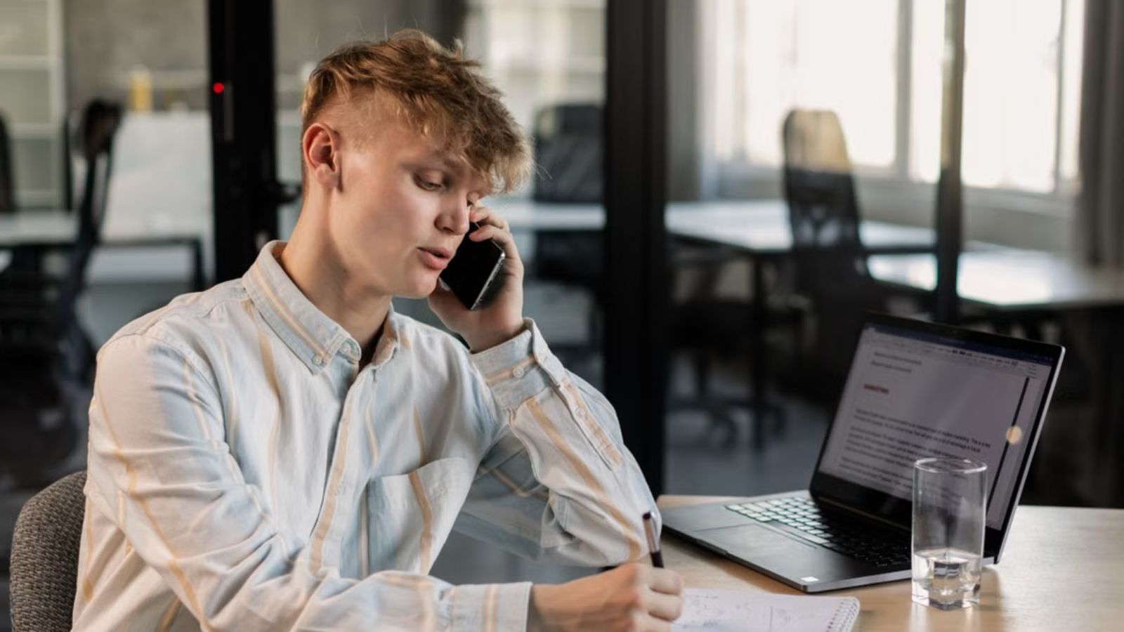 Man talking on his phone while at his work desk in the office