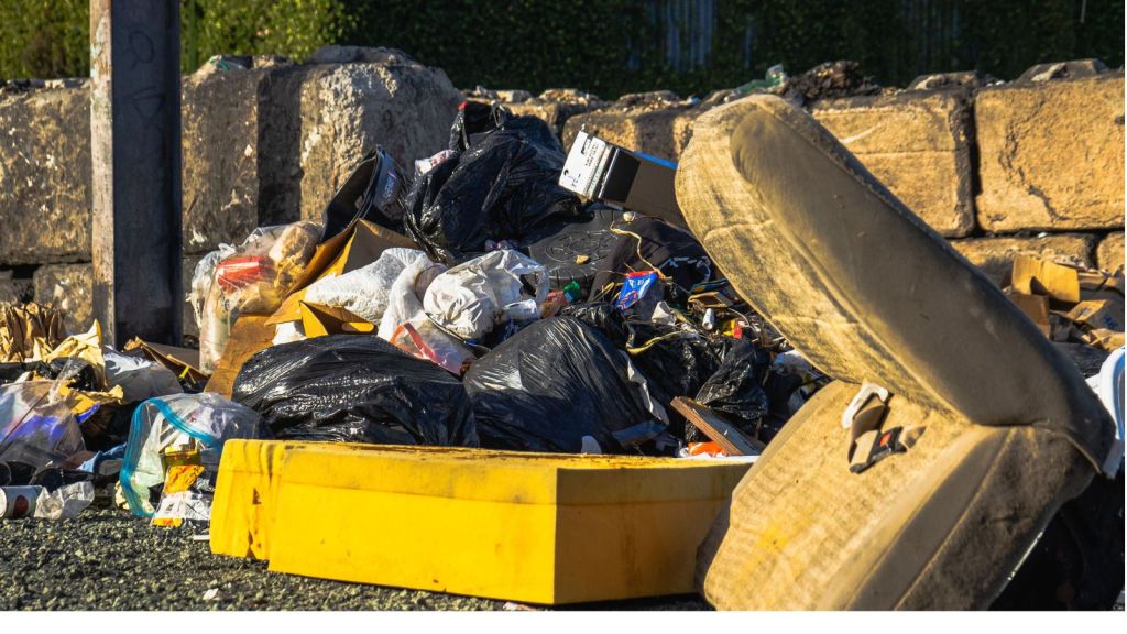 Outdoor scene of a garbage pile including a discarded mattress and various waste materials