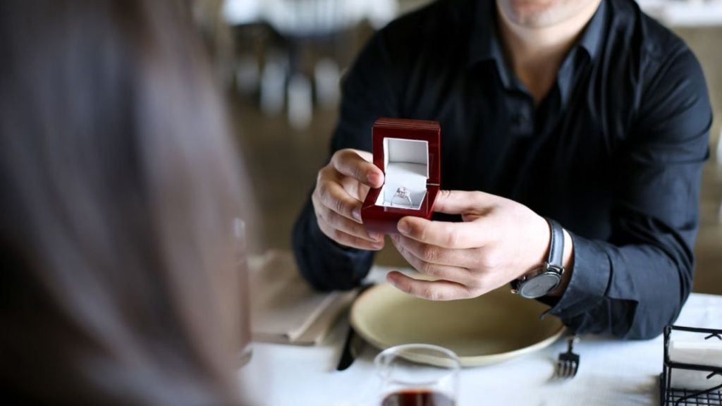 Man proposing and showing a ring to a woman while in a restaurant
