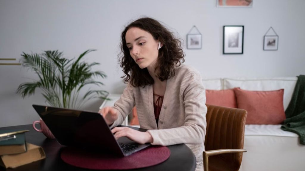 Woman with AirPods working in front of her laptop at the comfort of her home