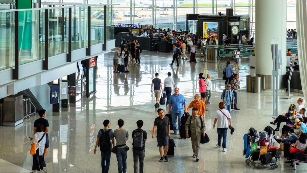 Busy airport with passengers walking, sitting, and waiting