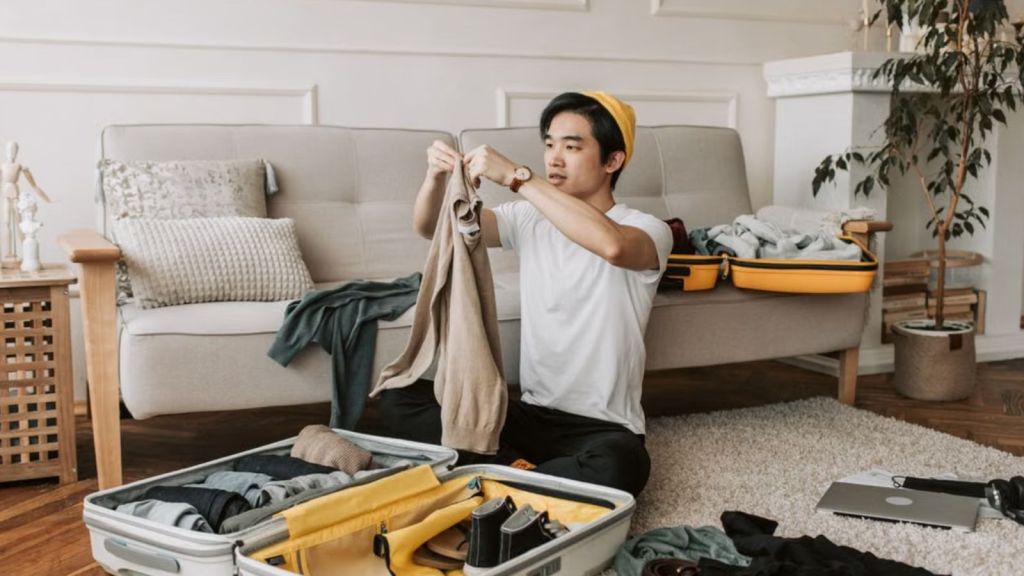 Man packing his clothes and shoes in a luggage