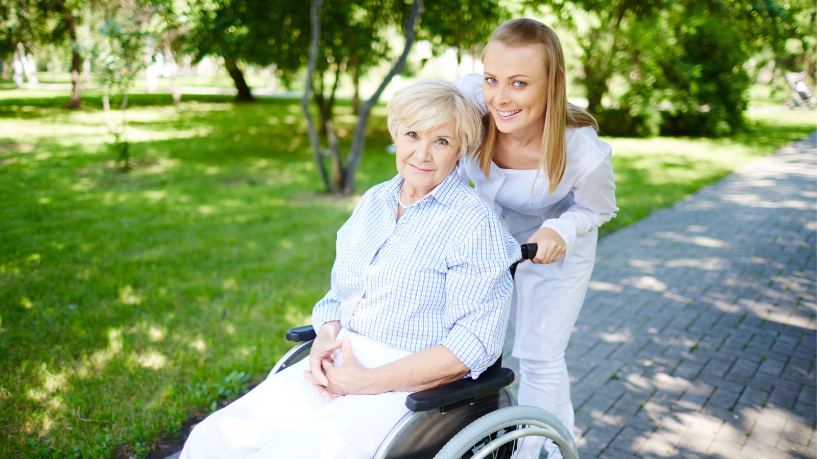 Woman smiling while pushing an elderly female in wheelchair