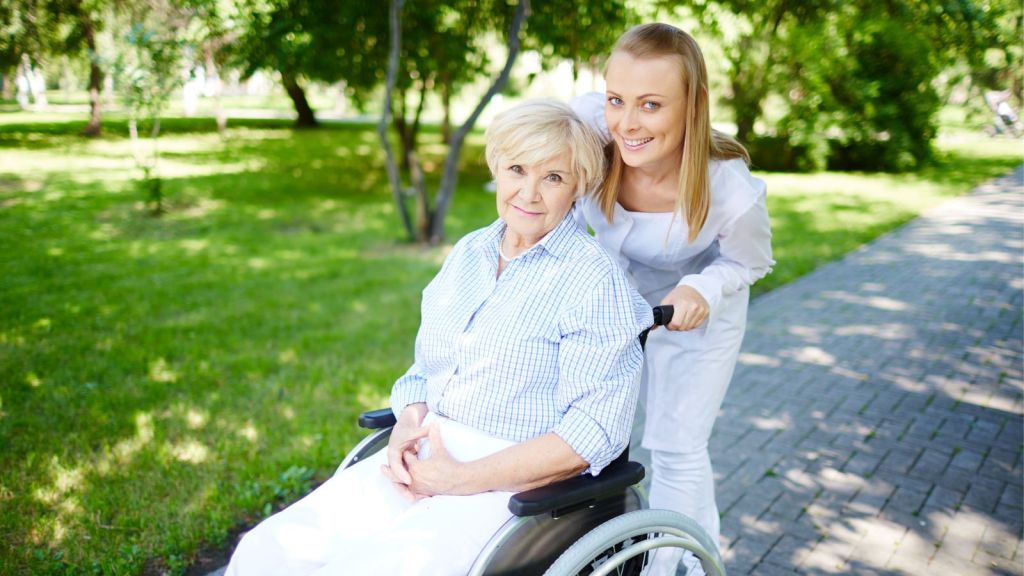 Woman smiling while pushing an elderly female in wheelchair