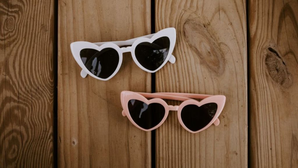 A pair of heart-shaped sunglasses for kids on wooden background
