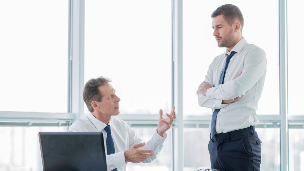 Boss passionately explaining work to an employee who's standing beside him