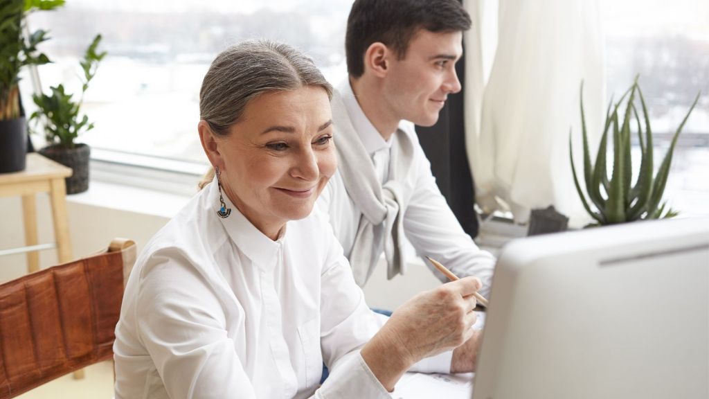 Woman smiling while looking at her computer screen with a man sitting beside her