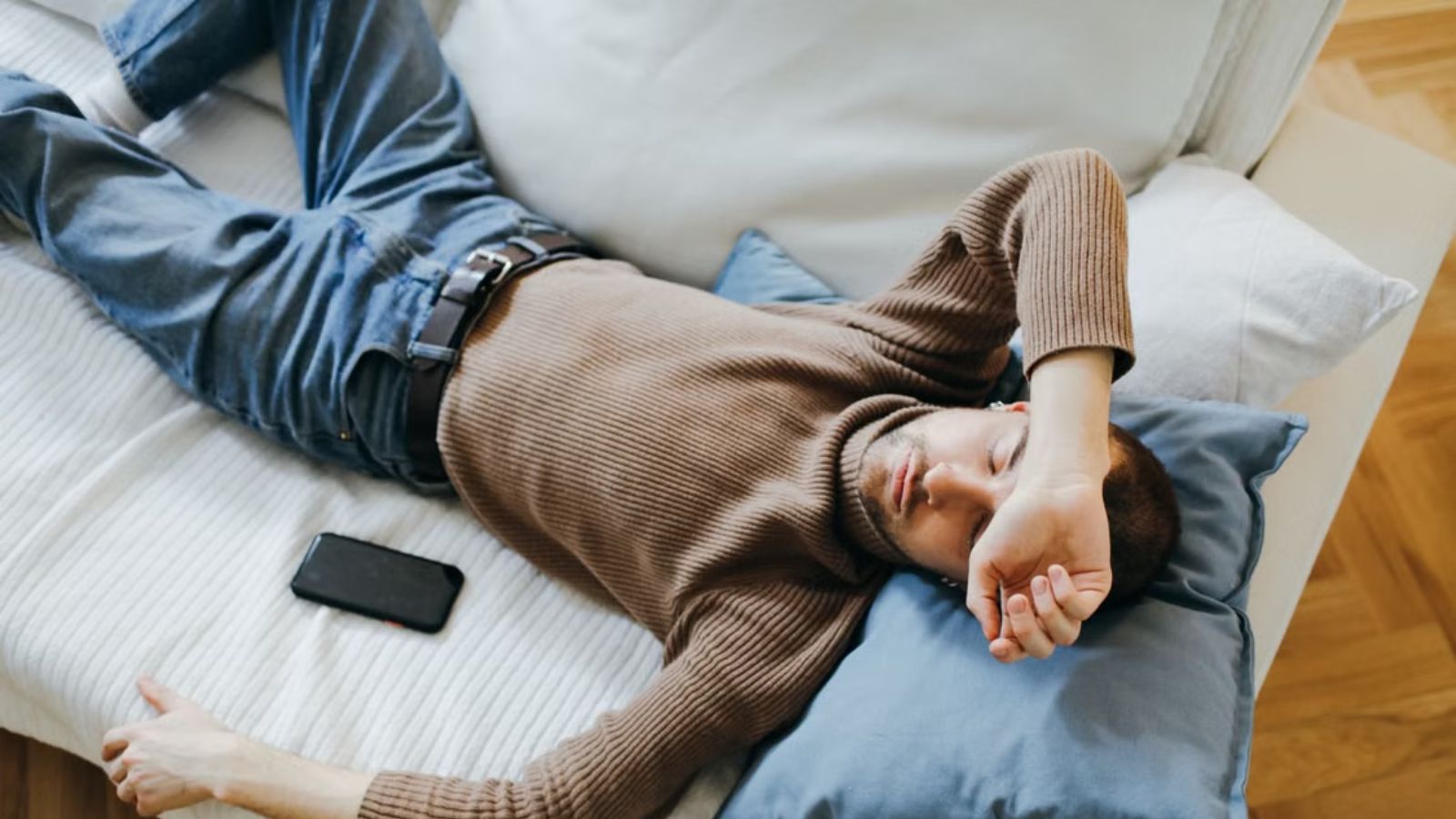 Exhausted man lying on a couch with his phone beside him